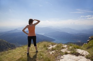 Woman standing on mountain top looking at mountain landscape and blue sky.
